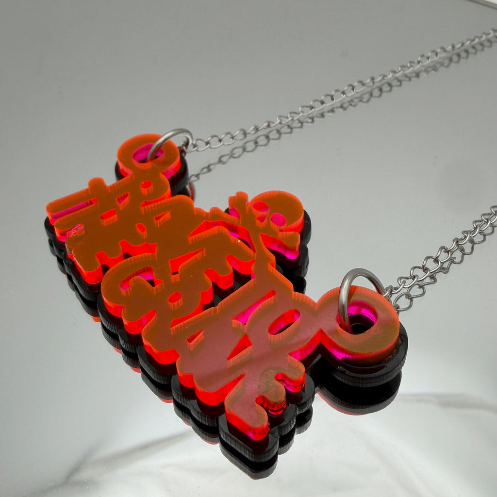 Rave To The Grave Neon Orange and Black Acrylic Necklace on mirrored background
